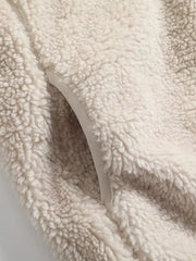 Beige sherpa zip-up jacket with chevron trim pocket detail.
