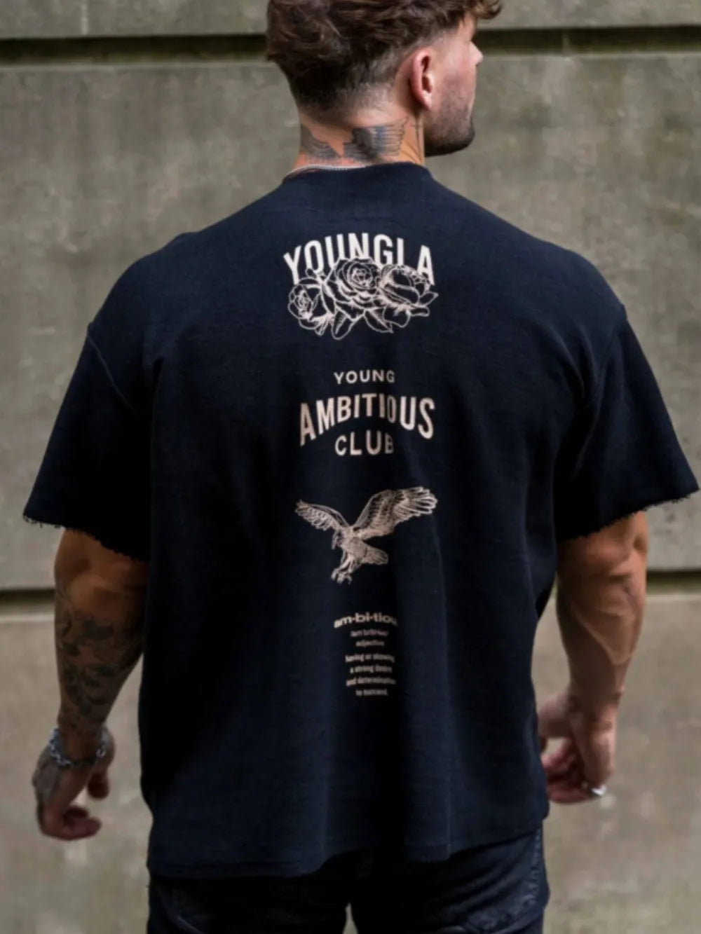 Black graphic tee with raw edges, rose and eagle print, and "Young Ambitious Club" text.