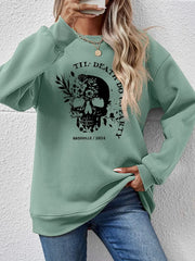 Sage green raglan sweatshirt with floral skull graphic and text