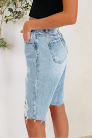 Light wash denim bermuda shorts with distressed details and frayed hem