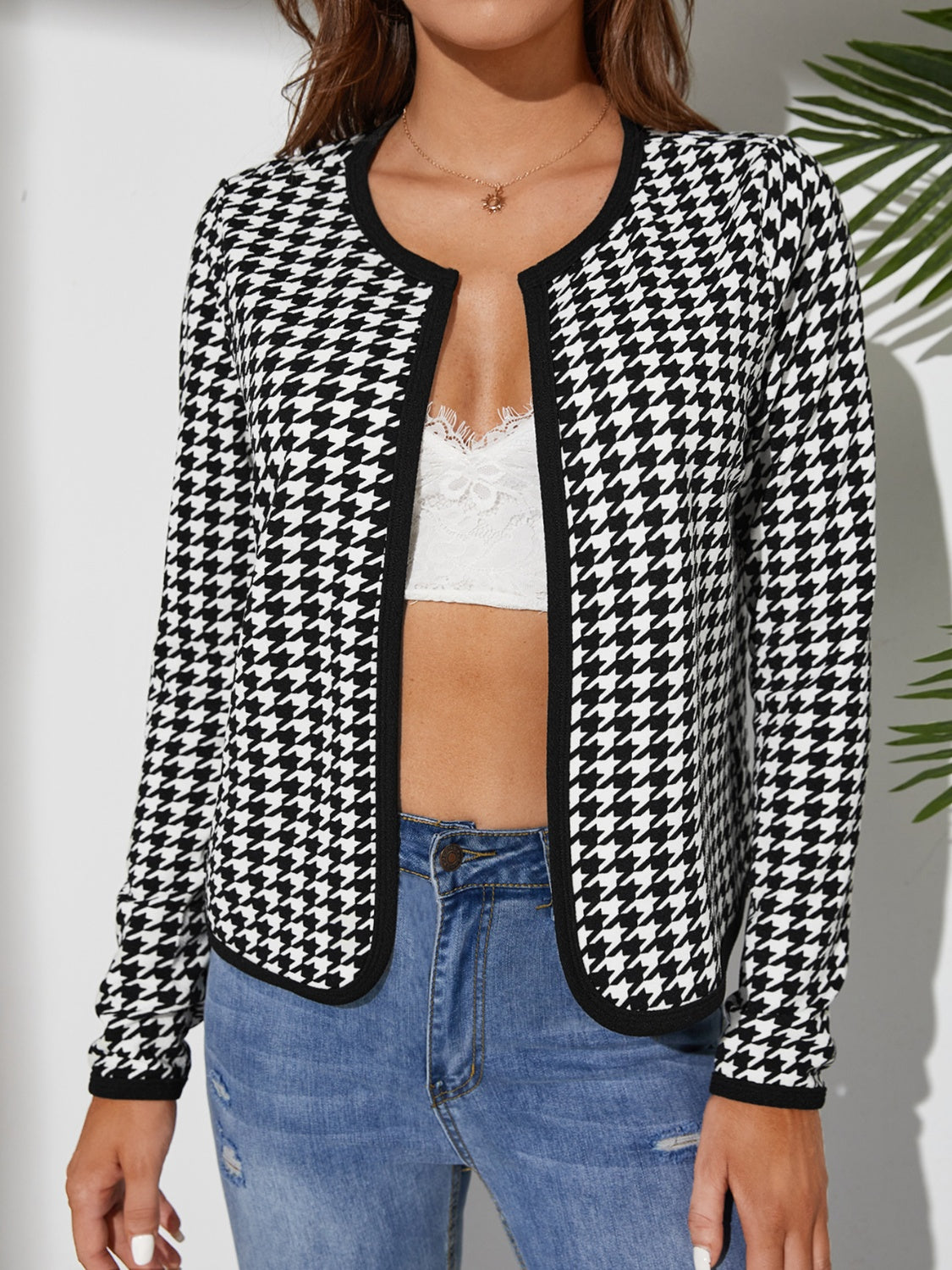 Black houndstooth edge-to-edge jacket with black trim and round neckline.