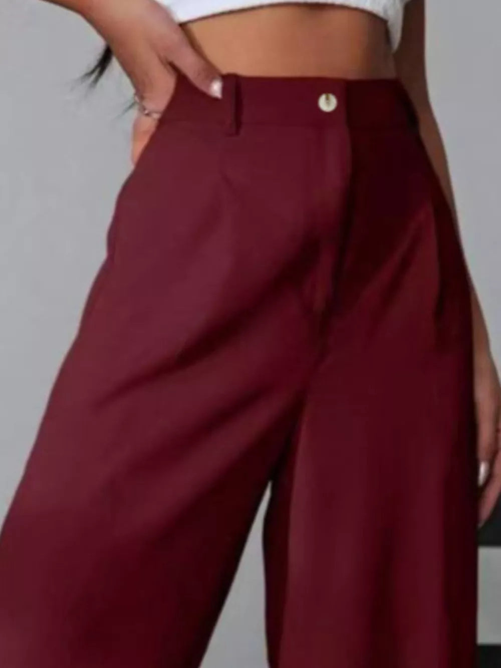 Burgundy high-waisted pleated wide-leg maternity trousers with button detail.
