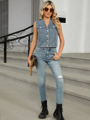 Cropped denim utility vest in medium wash with button front and chest pockets.