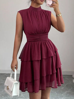 Sleeveless ruffle tiered dress in dark red with ruched bodice and mock neck.