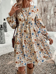Charming floral tiered dress with long sleeves and a-line cut in beige with blue and orange flowers.