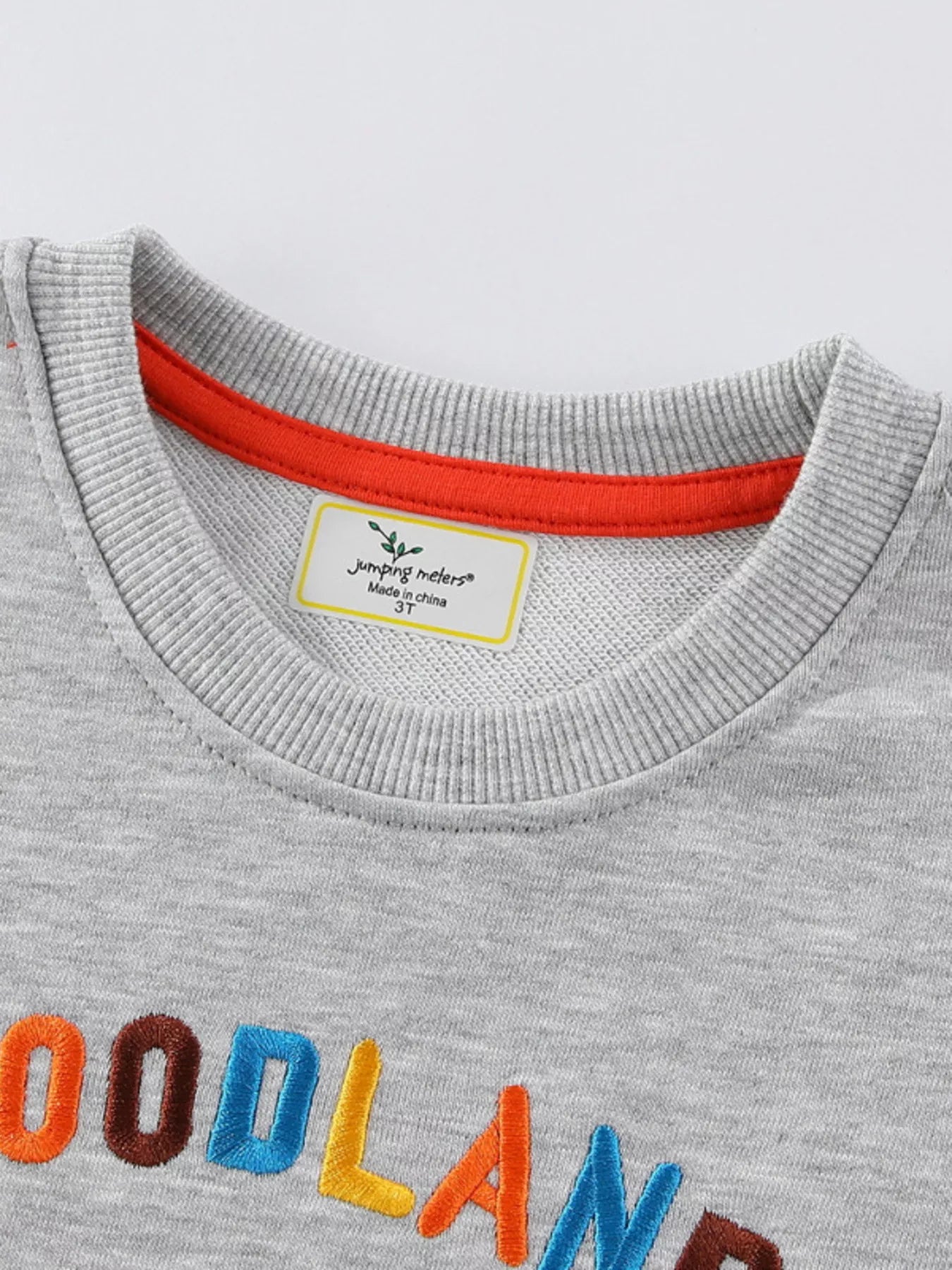 Gray baby sweatshirt with embroidered "WOODLAND" text and orange neckline trim.
