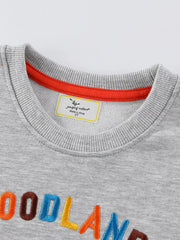 Gray baby sweatshirt with embroidered "WOODLAND" text and orange neckline trim.