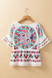 White peplum blouse with floral embroidery, ruffled sleeves, and a round neckline.