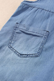 Medium wash denim romper with a chest pocket and adjustable straps detail.