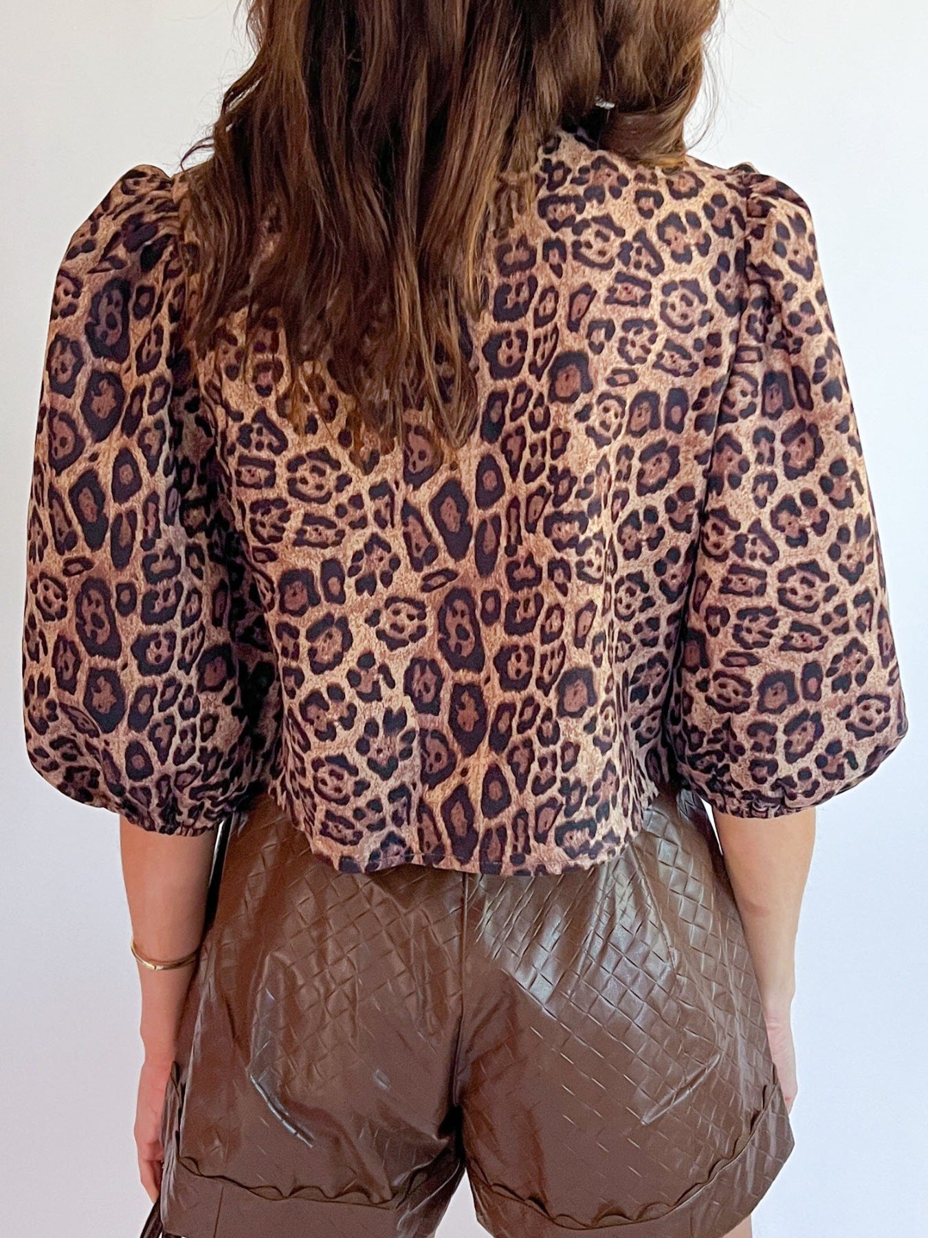Leopard print cropped blouse with puff sleeves and a bow tie detail.
