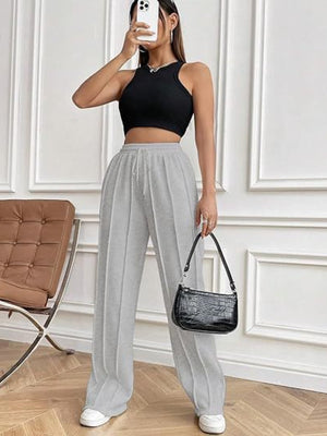 Gray pleated wide-leg lounge trousers with drawstring waist and a relaxed fit.
