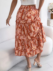 Orange floral midi skirt with tiered ruffles and elastic waist, styled with white heels.
