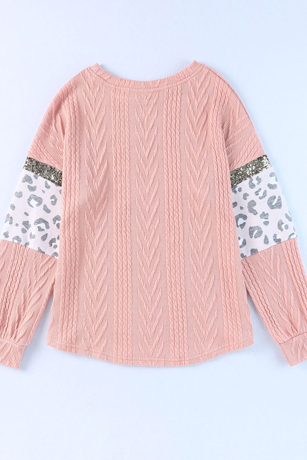 Pale blush sweater with textured chevron knit, leopard print sleeves, and sequin detail.