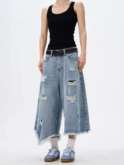 Distressed light wash denim wide-leg jeans with raw hem and frayed details.