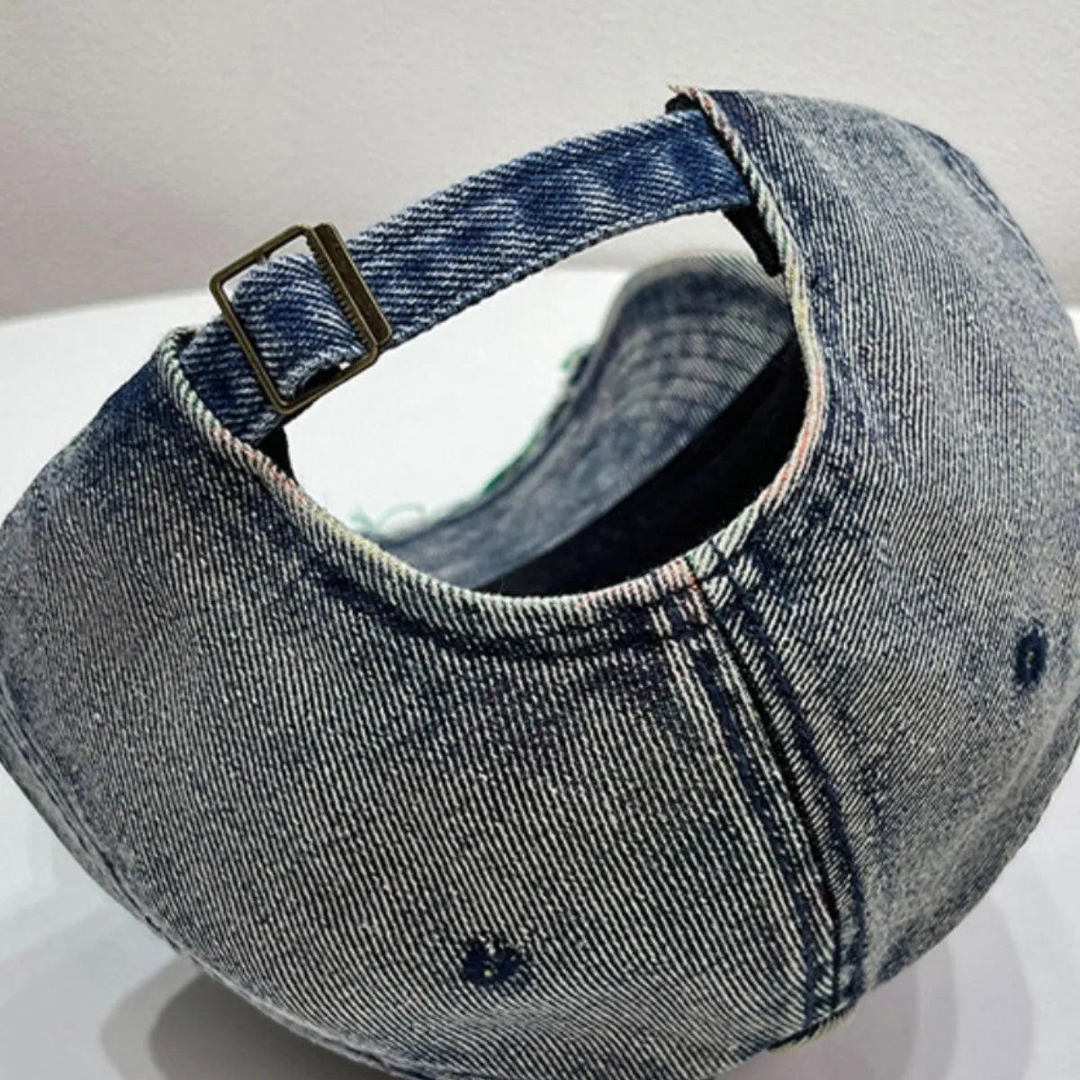 Distressed denim baseball cap with frayed edges and adjustable strap