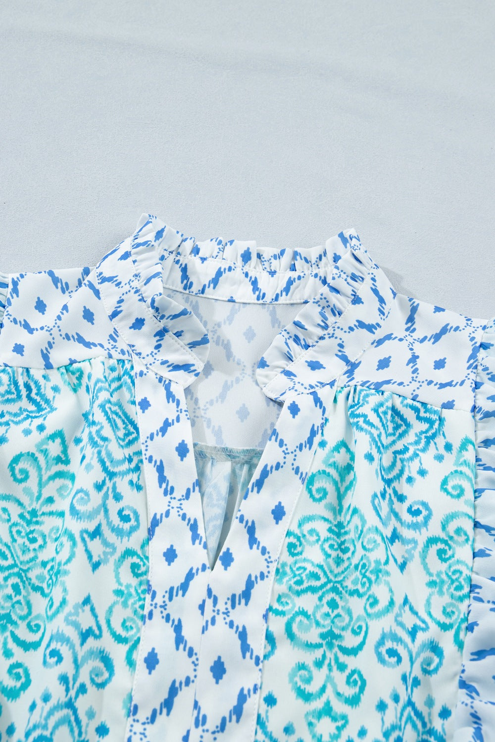 Patchwork mini dress with blue ikat and damask prints, V-neck, and ruffled collar.