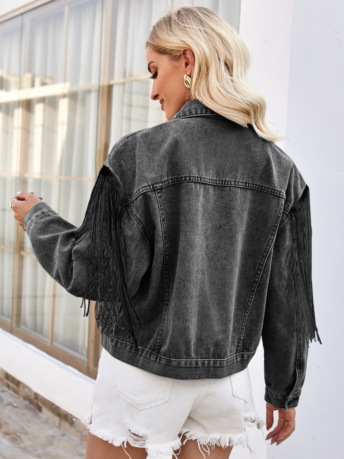 Black denim trucker jacket with fringe trim on sleeves and back.