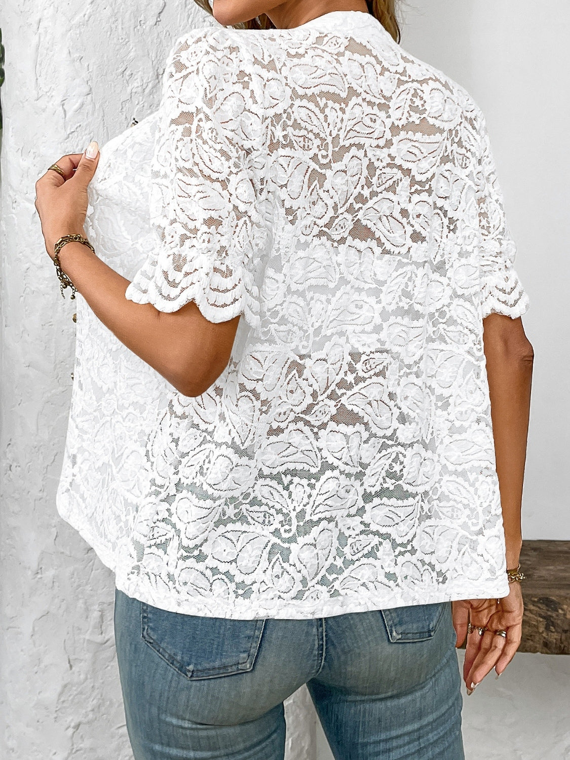 White floral lace blouse with mandarin collar and scalloped short sleeves.
