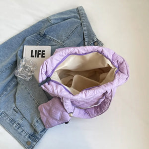 Quilted lilac tote bag with open top and purple trim, shown with a denim jacket.
