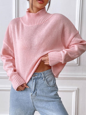 Blush pink ribbed turtleneck knit sweater with a cropped length and cuffed sleeves.