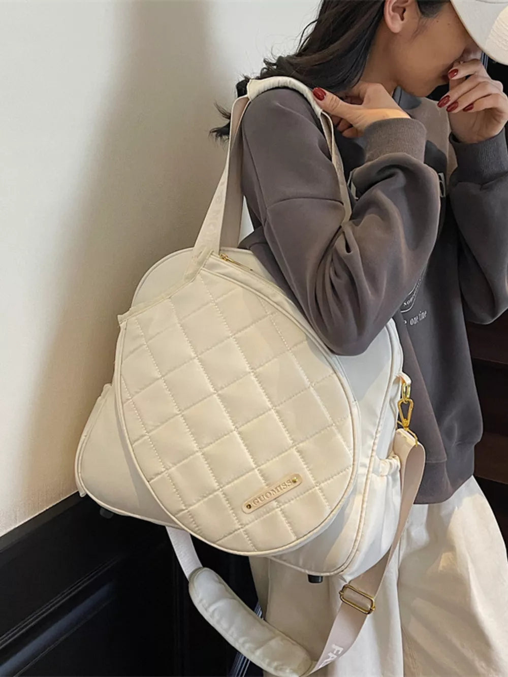 Quilted off-white Oxford bag for racket storage with adjustable strap.