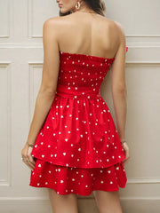 Red smocked strapless mini dress with white hearts, tiered skirt, and bow detail.