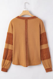 Caramel waffle knit henley top with contrast stitching and striped sleeves.