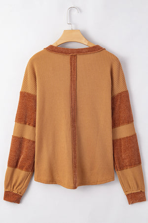 Caramel waffle knit henley top with contrast stitching and striped sleeves.