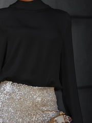 Black silk blouse with a draped back detail, styled with a sequined skirt.