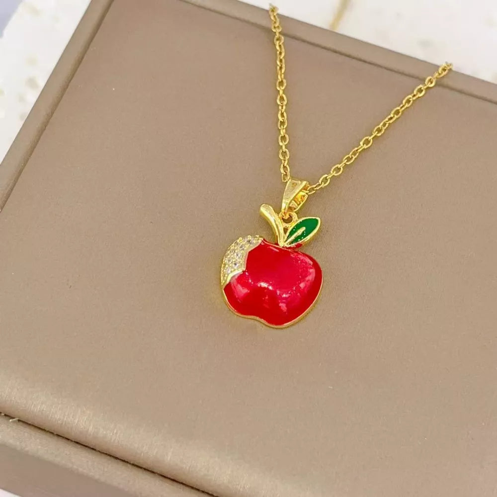 Gold-plated necklace with a red apple pendant, green leaf, and crystal accents.