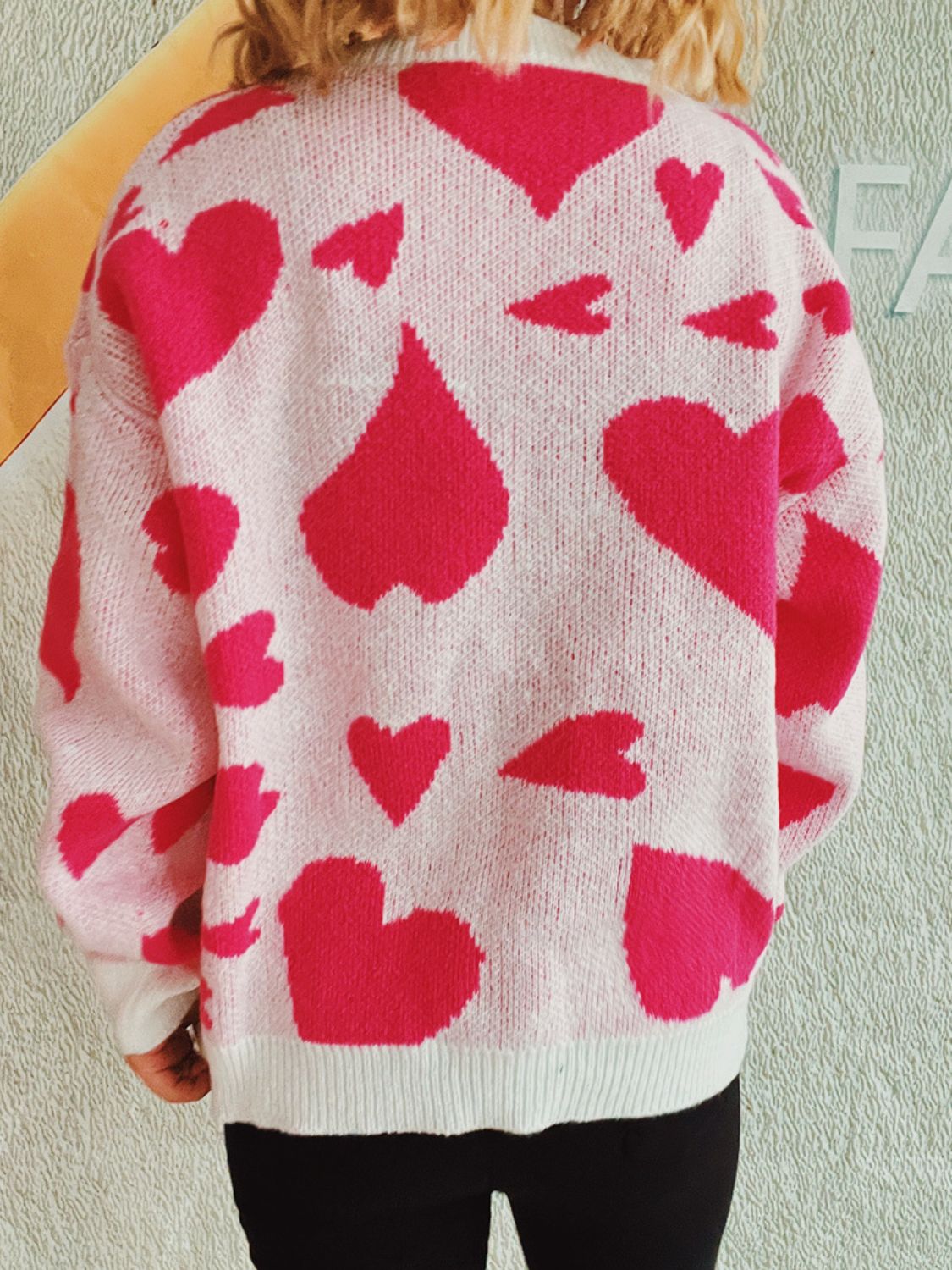 Heart motif knit sweater in pink with a scattered heart pattern, crew neck, long sleeves.