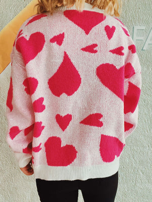 Heart motif knit sweater in pink with a scattered heart pattern, crew neck, long sleeves.