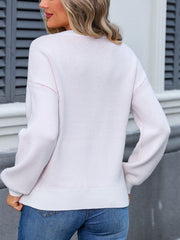 Blush pink acrylic knit sweater with long sleeves and crew neck, styled with jeans.