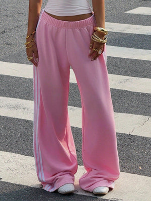 Pink relaxed wide leg sweatpants with white side stripes and elasticated waist.