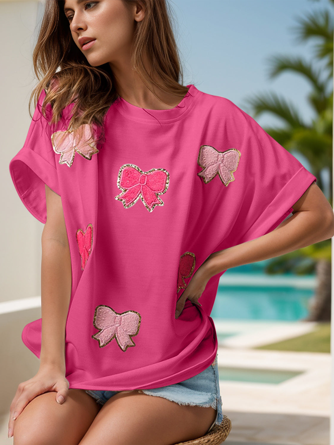 Hot pink oversized tee with sequin bow embellishments and rolled sleeves.