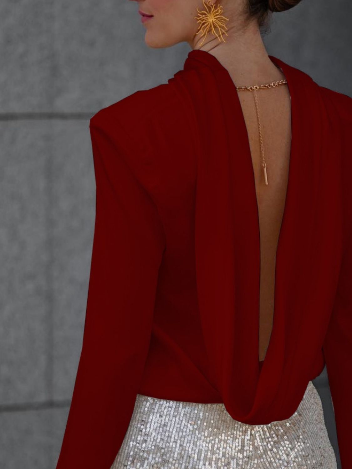 Burgundy silk blouse with draped back and gold chain detail.