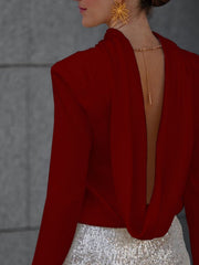 Burgundy silk blouse with draped back and gold chain detail.