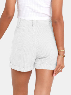White corduroy high-waist shorts with pleats and cuffed hems.