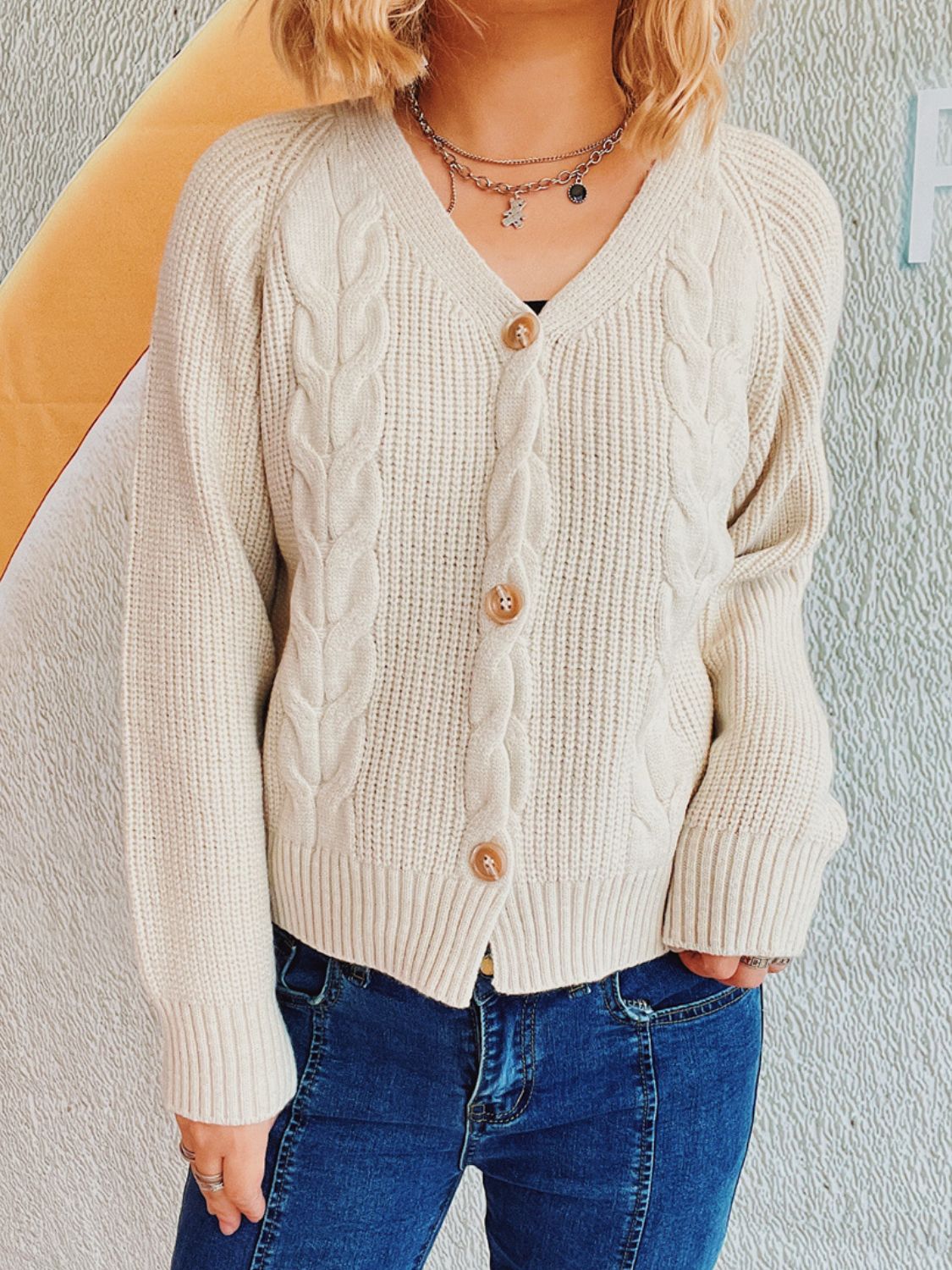 Beige cable knit raglan cardigan with button front and V-neck.