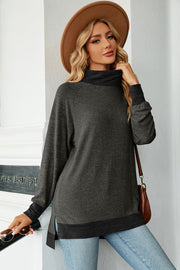 Colorblock raglan turtleneck tunic in dark gray with black accents, side slits, and cuffed sleeves.