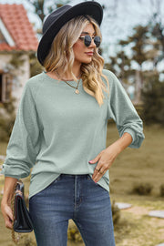 Light green waffle knit eyelet raglan sleeve top with crew neck and cuffed sleeves.