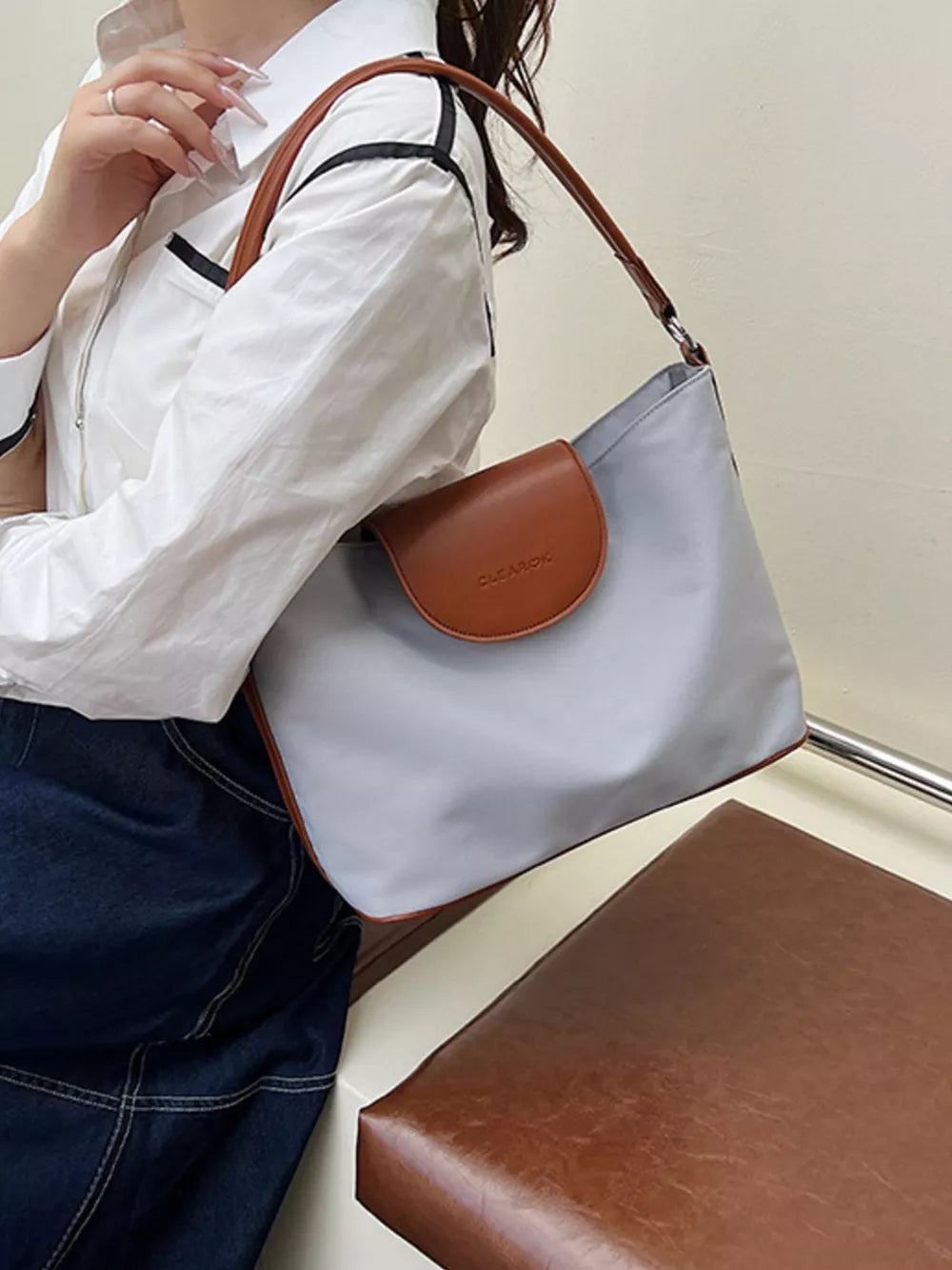 Chic canvas hobo crossbody bag in gray with brown trim and flap.