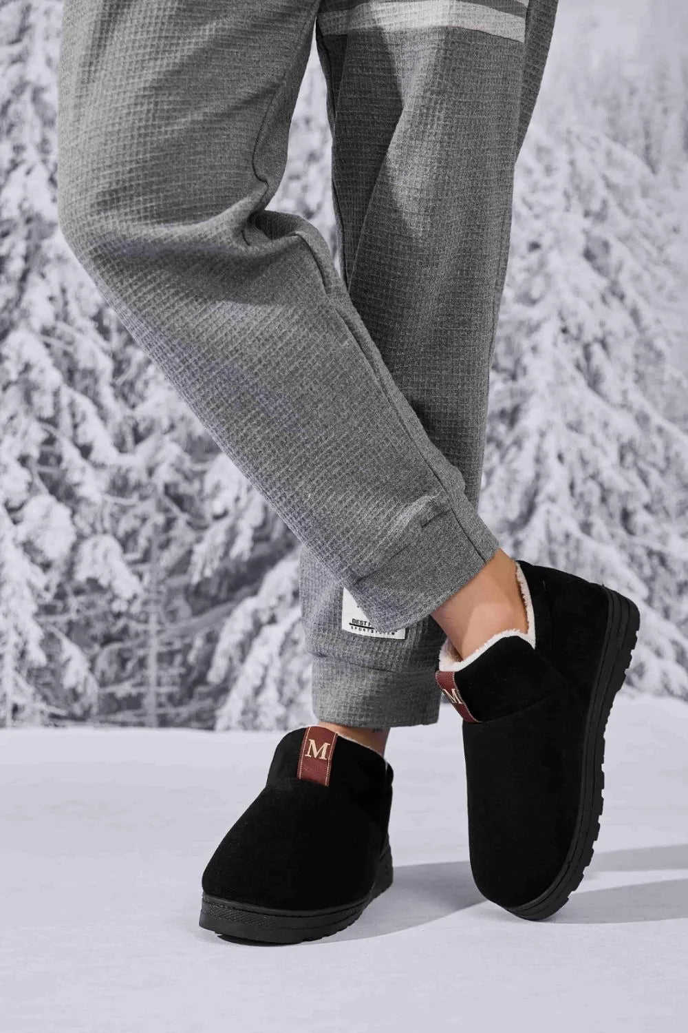 Black suede shearling-lined house booties with red tab detail.