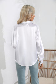 White glossy satin button-down blouse with long sleeves and button cuffs.