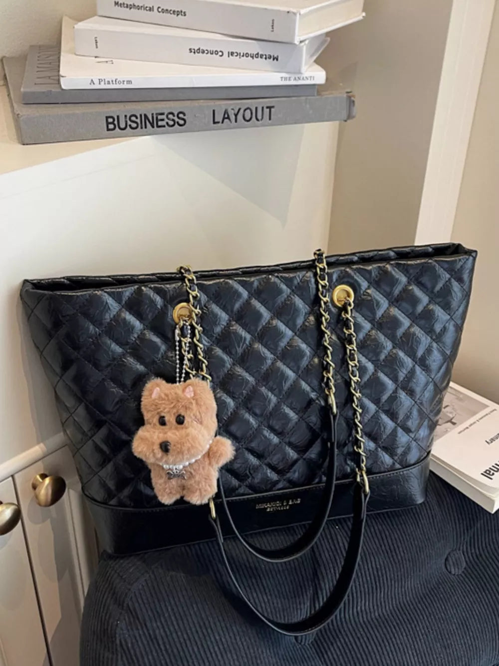 Black quilted shoulder bag with gold chain strap and teddy bear charm