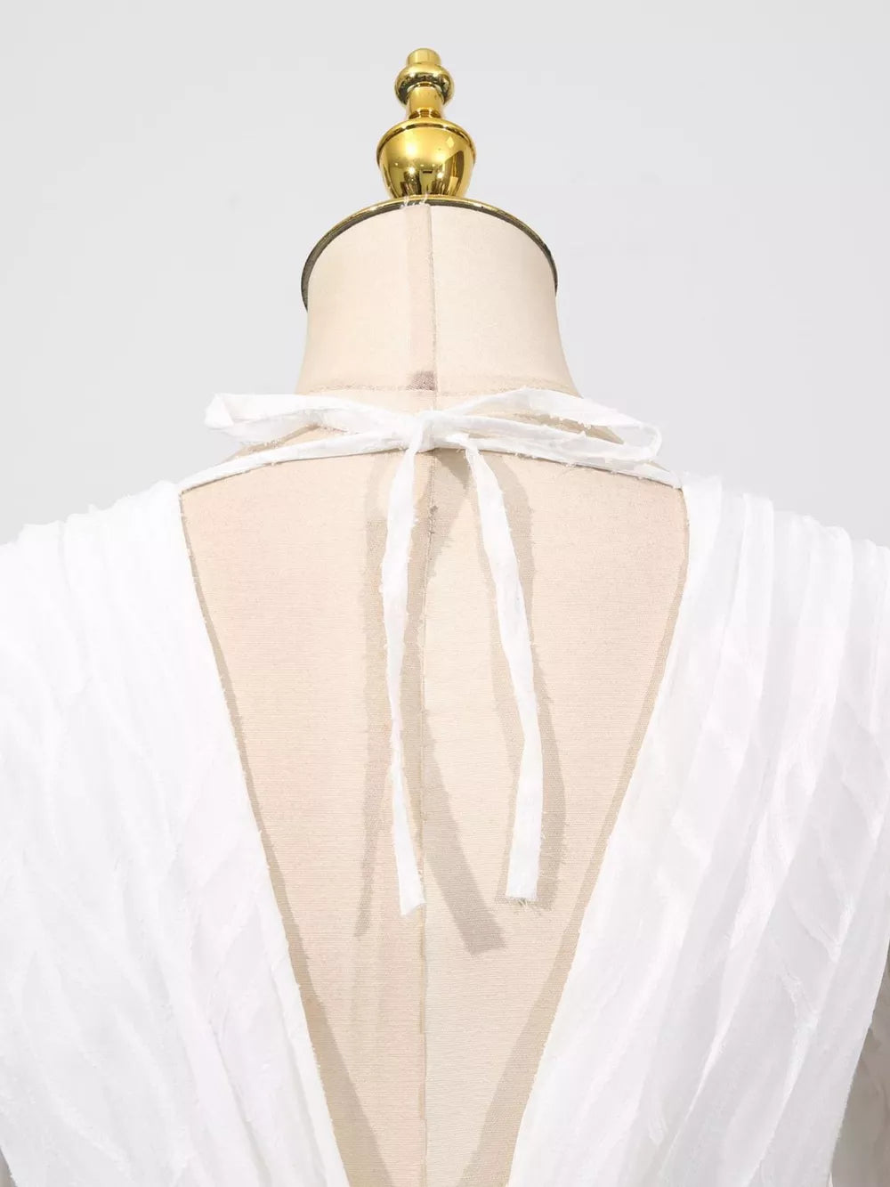 White maxi dress with V-neck and tie detail on back, textured fabric.