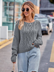 Charcoal cable-knit sweater with a crew neck and long sleeves, styled with light wash jeans.