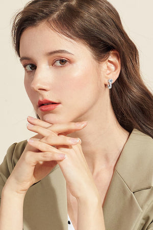 Silver pavé and solitaire hoop earrings worn by a woman.