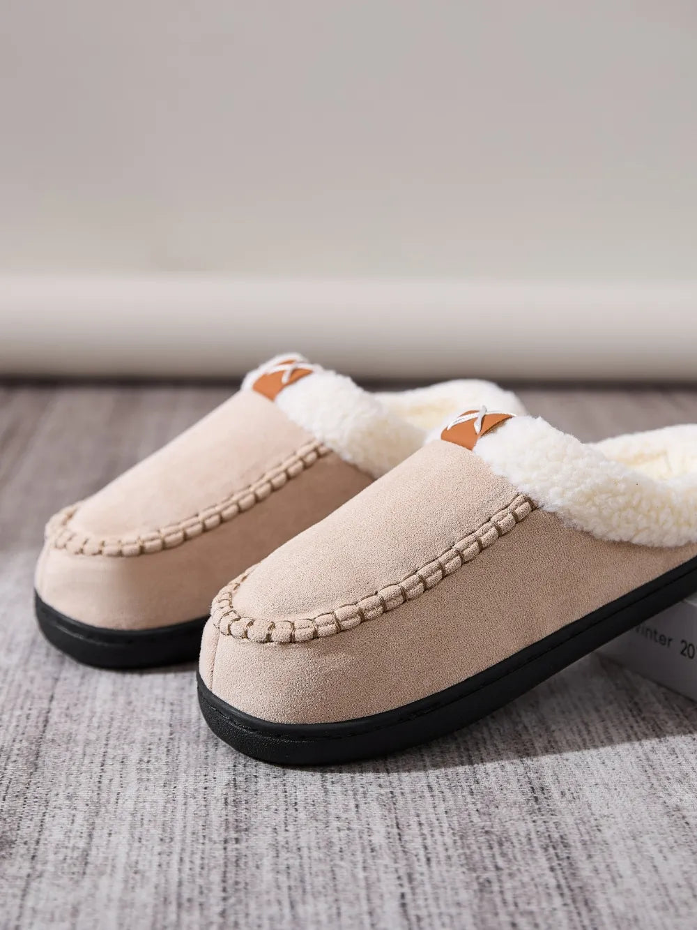 Suede shearling-lined moccasin slides in caramel with decorative stitching and a brown accent tab.