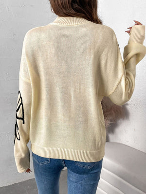 Pastel yellow acrylic knit sweater with embroidered floral motif on sleeve.